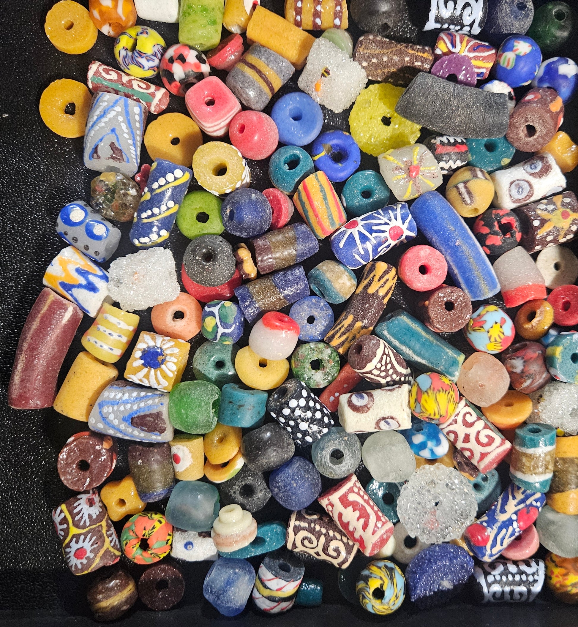 Close-up of layered assorted Krobo artisan beads showing mixed sizes and colors.