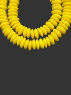 Close up image of handcrafted Sankofa Gold Ashanti glass rondelle beads from Ghana made from recycled glass featuring large holes and a vibrant matte artisan finish.