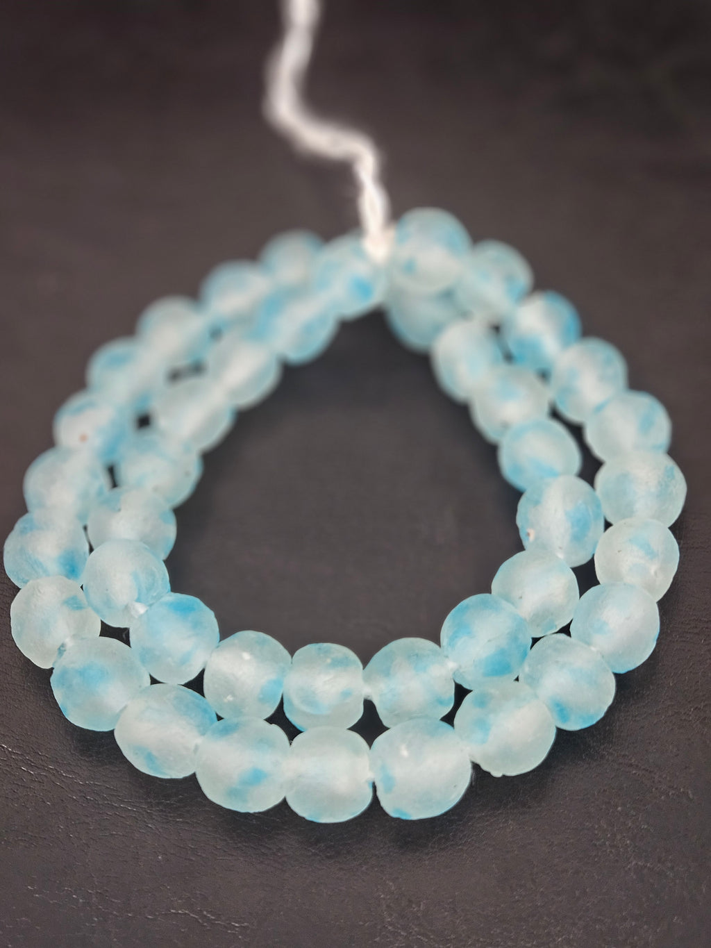 Authentic African beads from Ghana featuring chunky translucent sky blue recycled glass Krobo beads with a frosted matte finish handcrafted by artisans for sustainable jewelry making, designer collections, and cultural materials.