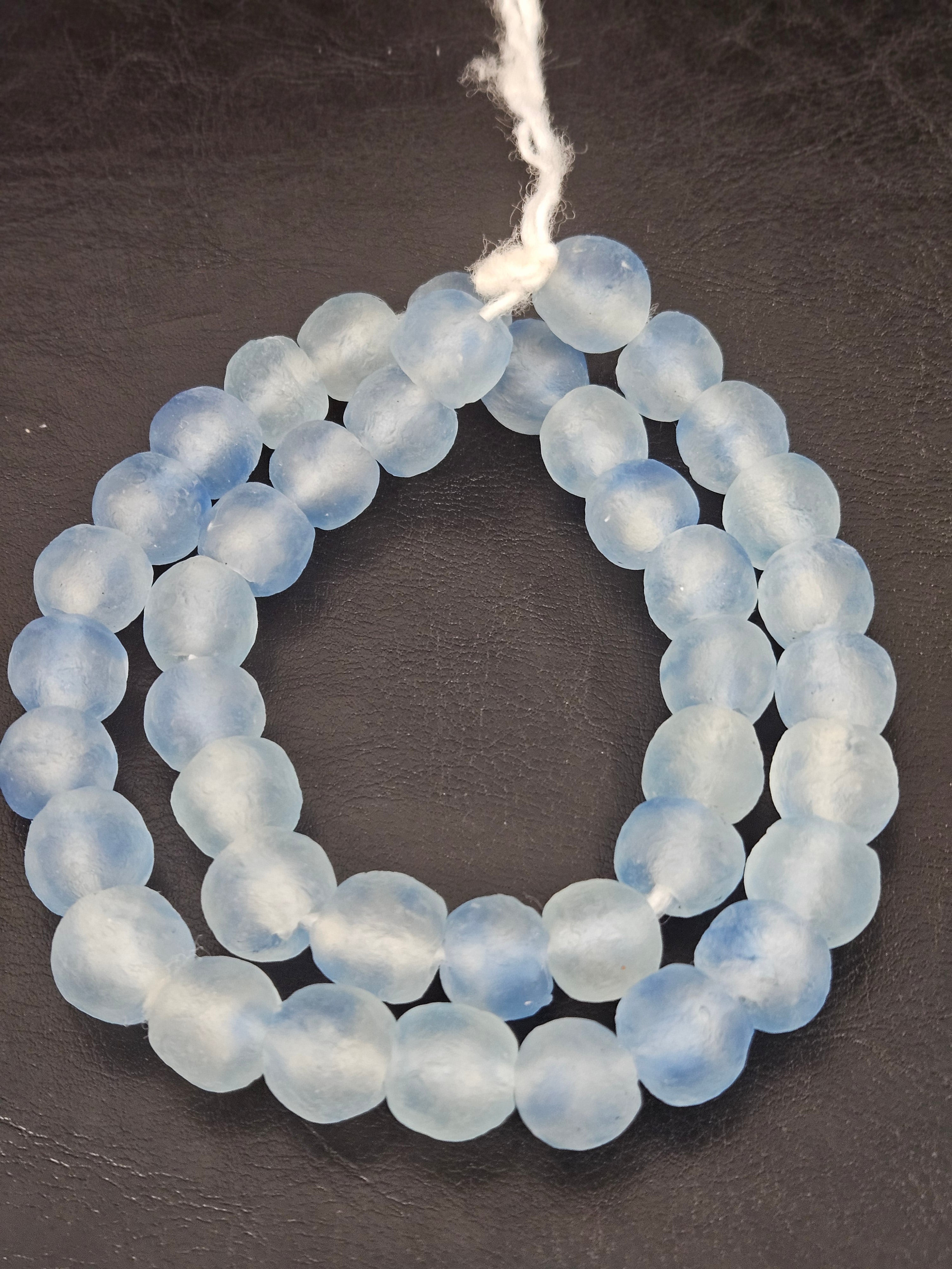 Authentic African beads from Ghana featuring chunky ice blue translucent recycled glass Krobo beads handcrafted by artisans with a matte frosted finish for sustainable jewelry making.