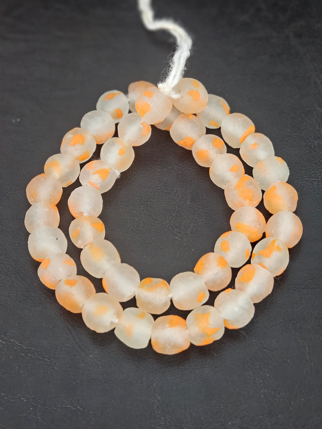 Authentic African orange speckled translucent Krobo recycled glass beads handcrafted in Ghana featuring frosted handmade round beads created from recycled glass for luxury jewelry making.