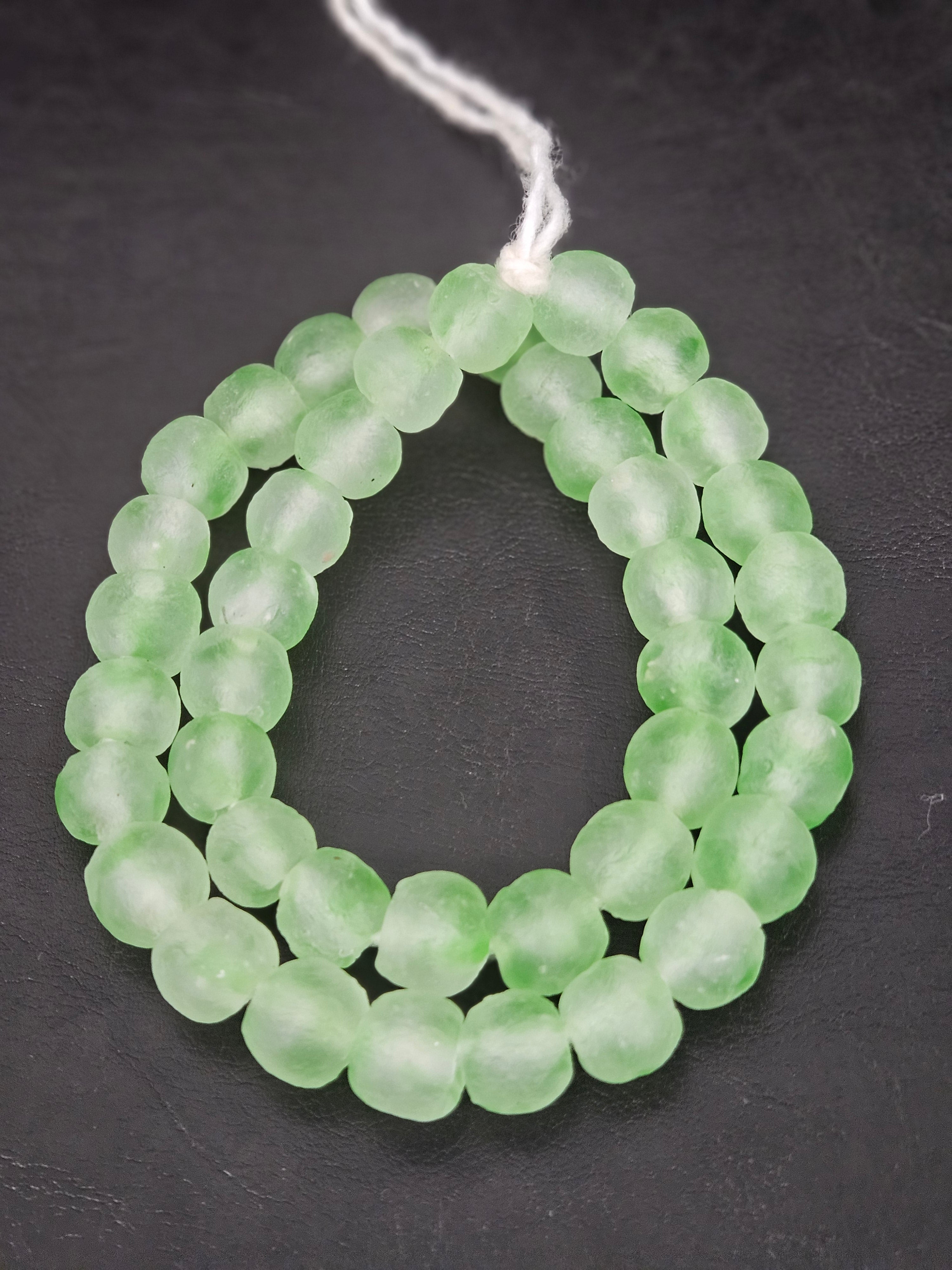 Authentic mint green translucent Krobo recycled glass beads handcrafted in Ghana featuring frosted handmade round beads for luxury jewelry making, sustainable designer collections, and contemporary artisan creations.