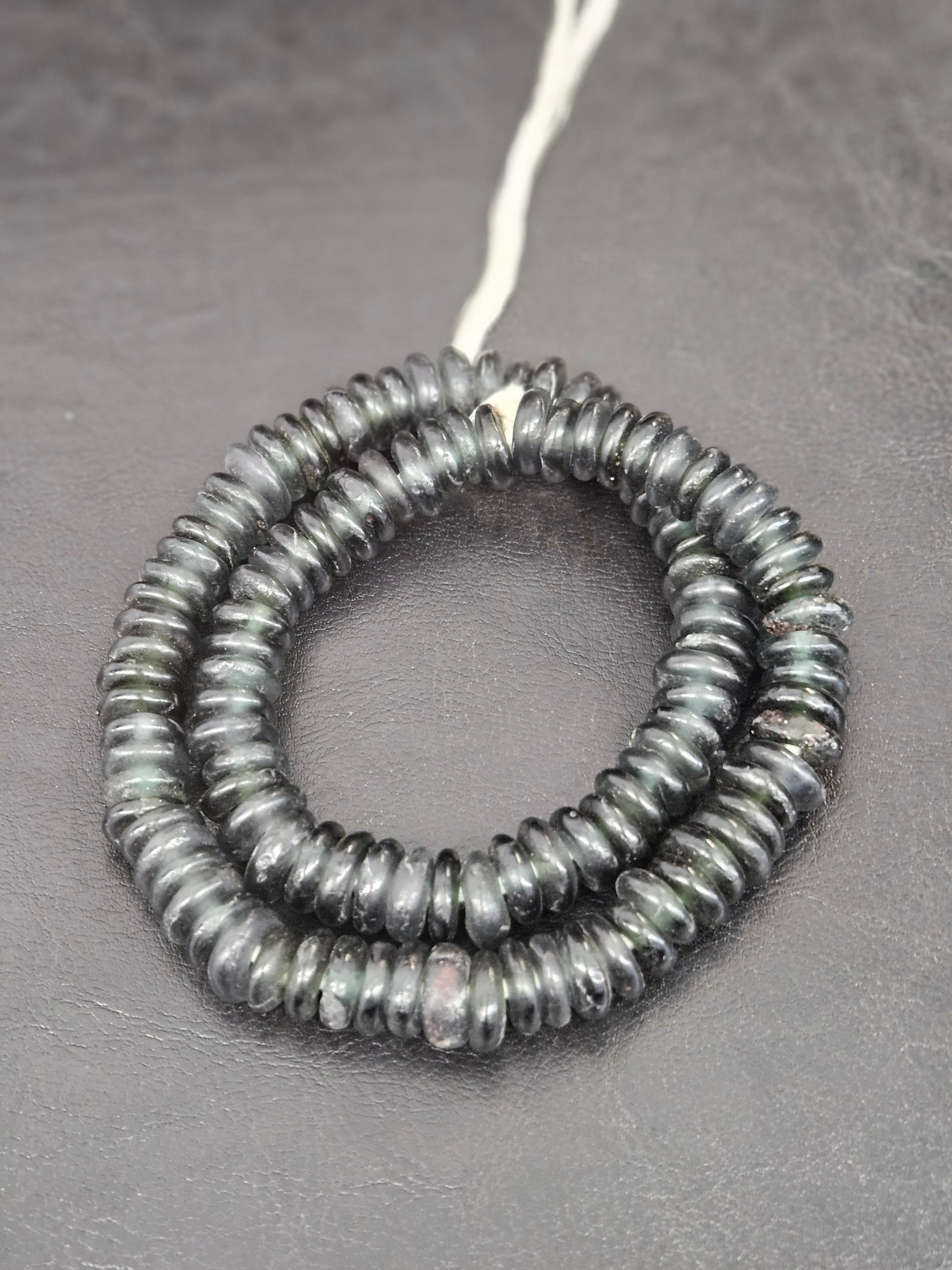 Authentic handmade black Krobo translucent recycled glass rondelle beads from Ghana with matte frosted finish arranged as a full strand for jewelry making and wholesale design.