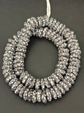Authentic handcrafted black and white Fused Krobo Rondelle Recycled Glass Beads from Ghana featuring intricate artisan graphic patterns arranged as a full designer strand for luxury jewelry making and wholesale sourcing.