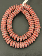 Authentic handcrafted Coral Fused Krobo Rondelle Recycled Glass Beads from Ghana featuring intricate ivory and black artisan patterns arranged as a full strand for jewelry designers, collectors, and sustainable luxury jewelry making.