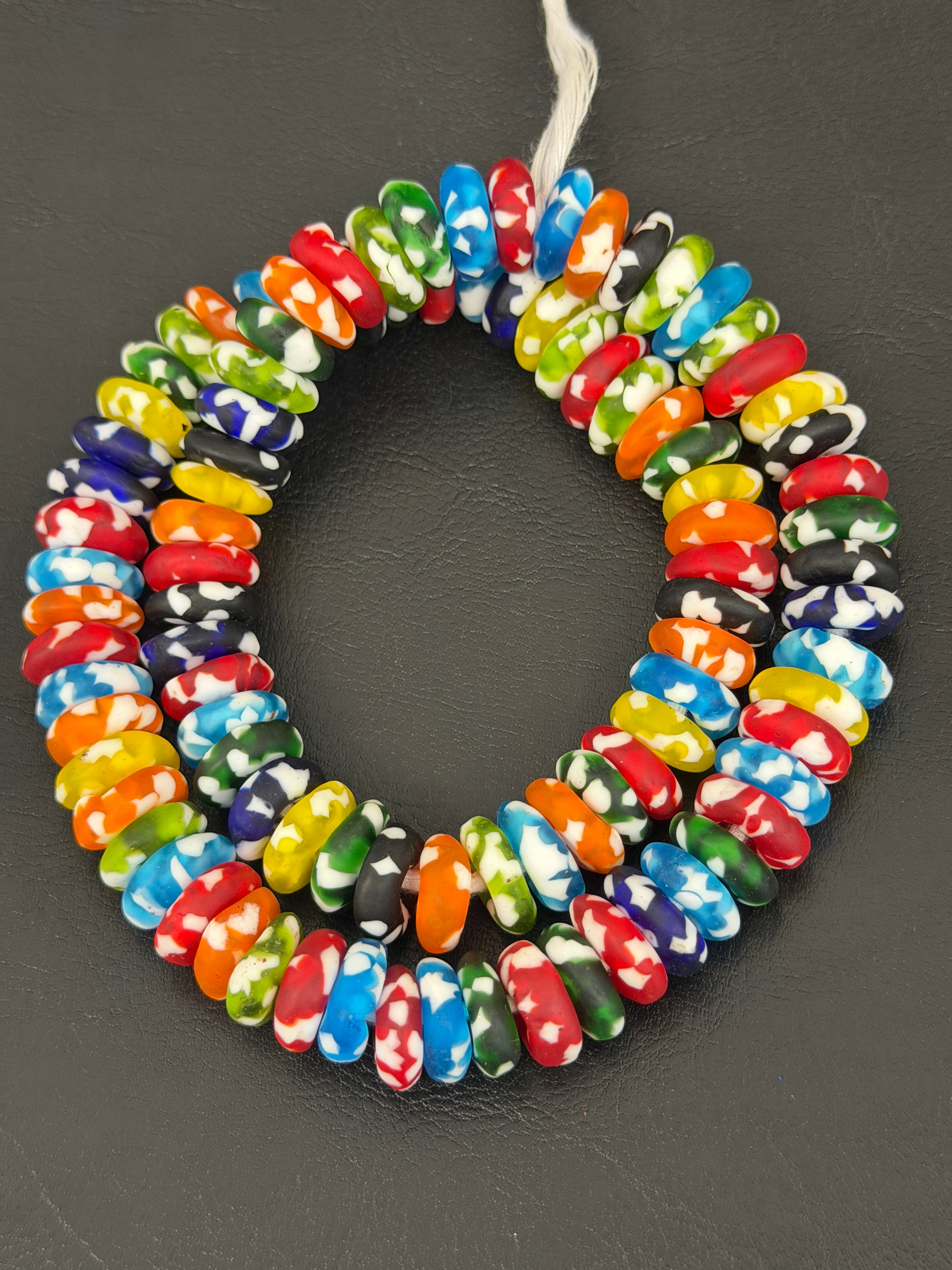 Authentic handcrafted Designer Mix Fused Krobo Rondelle Recycled Glass Beads from Ghana featuring blue, green, yellow, orange, red, black, and white artisan patterns arranged as a full strand for jewelry making and wholesale sourcing.