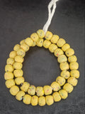 Authentic handcrafted golden ochre Krobo powdered glass beads from Ghana featuring organic round recycled glass beads with matte finish and colorful artisan speckles.