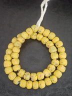 Authentic handcrafted golden ochre Krobo powdered glass beads from Ghana featuring organic round recycled glass beads with matte finish and colorful artisan speckles.