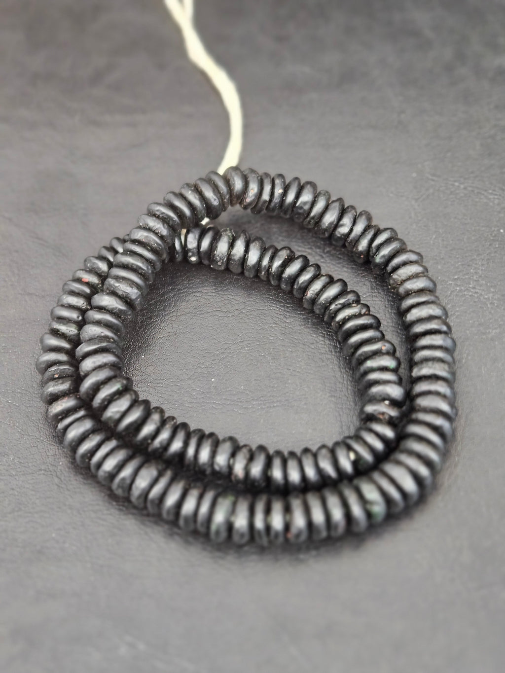 Authentic handmade matte black Krobo translucent recycled glass rondelle beads from Ghana featuring a soft matte finish for jewelry making, designer collections, and wholesale sourcing.