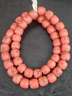 Authentic handcrafted matte coral Krobo powdered glass beads from Ghana made from recycled glass featuring rounded 13–14mm artisan beads with natural speckled finish on strand.