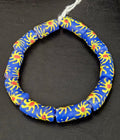 Authentic Painted Krobo Glass Tube Beads handcrafted in Ghana featuring matte royal blue recycled glass tube beads decorated with hand-painted golden yellow sunburst motifs and terracotta red accents for statement jewelry and artisan design.
