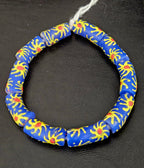 Authentic Painted Krobo Glass Tube Beads handcrafted in Ghana featuring matte royal blue recycled glass tube beads decorated with hand-painted golden yellow sunburst motifs and terracotta red accents for statement jewelry and artisan design.