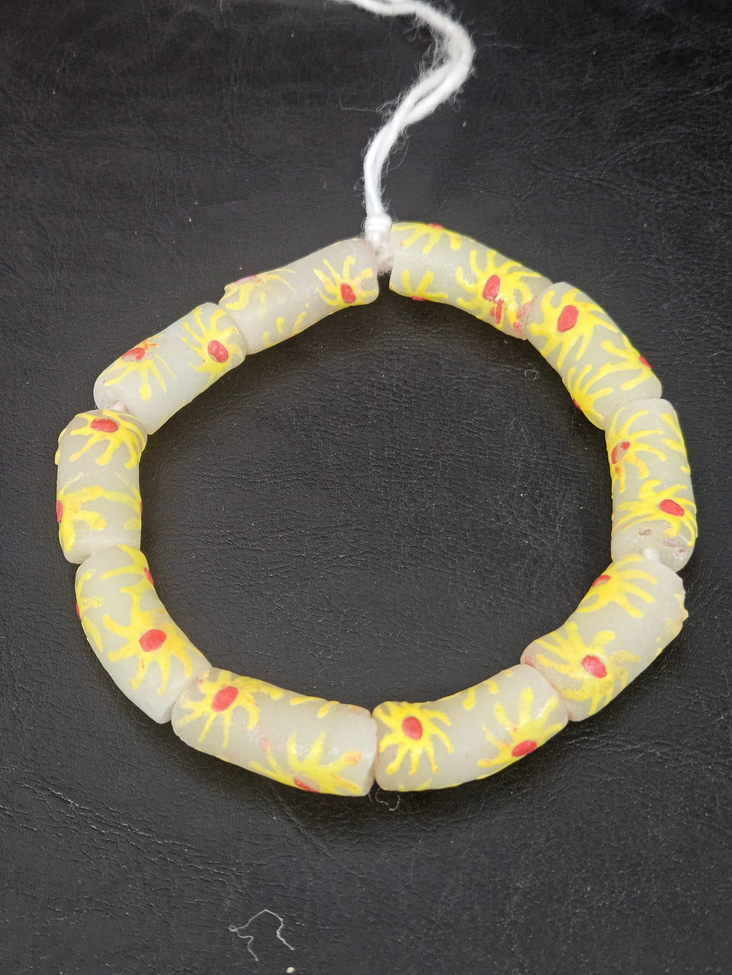 Authentic Painted Krobo Glass Tube Beads handcrafted in Ghana featuring matte soft ivory recycled glass tube beads decorated with hand-painted golden yellow sunburst motifs and terracotta red accents for statement jewelry and artisan design.