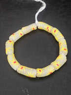 Authentic Painted Krobo Glass Tube Beads handcrafted in Ghana featuring matte soft ivory recycled glass tube beads decorated with hand-painted golden yellow sunburst motifs and terracotta red accents for statement jewelry and artisan design.