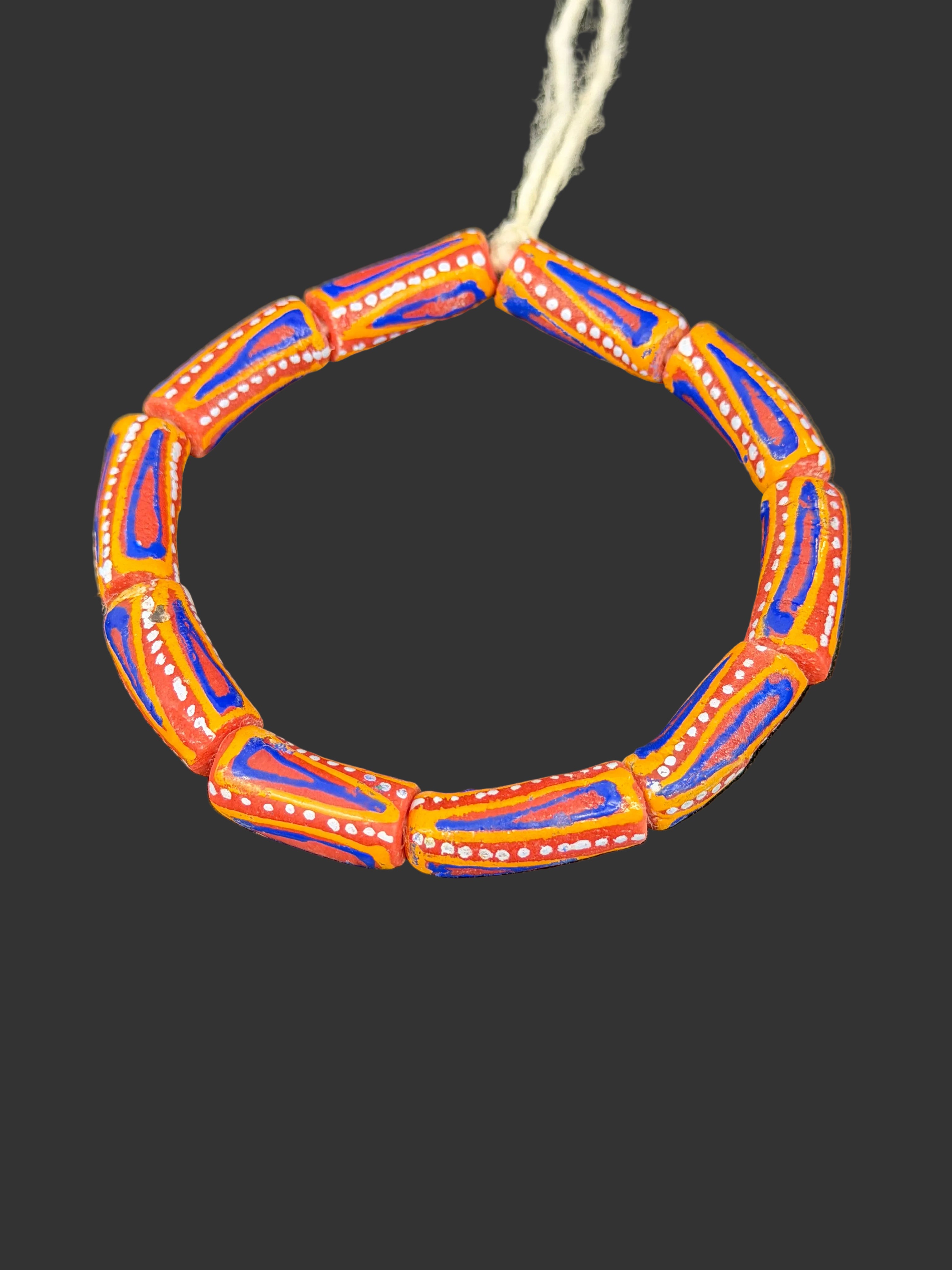 Handcrafted orange blue and white painted Krobo glass beads from Ghana featuring traditional geometric patterns on recycled glass tube beads.