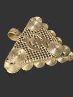 Close view of handcrafted Ghanaian brass pendant showing the central Gye Nyame symbol, latticework, and concentric spiral details.