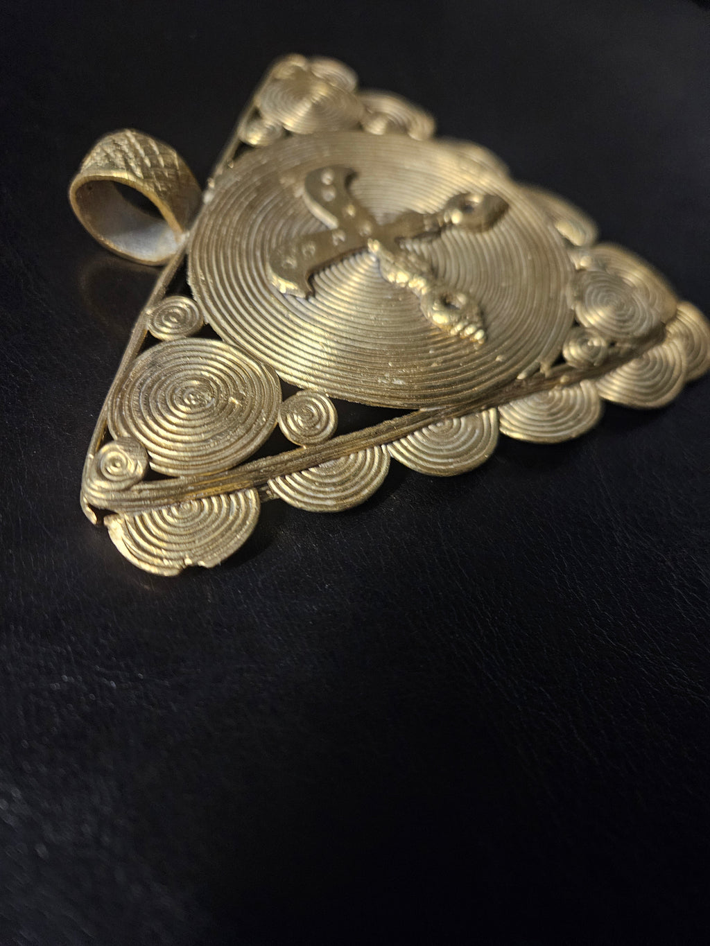 Large textured bail at the top of a handcrafted Ghanaian Akofena brass pendant.
