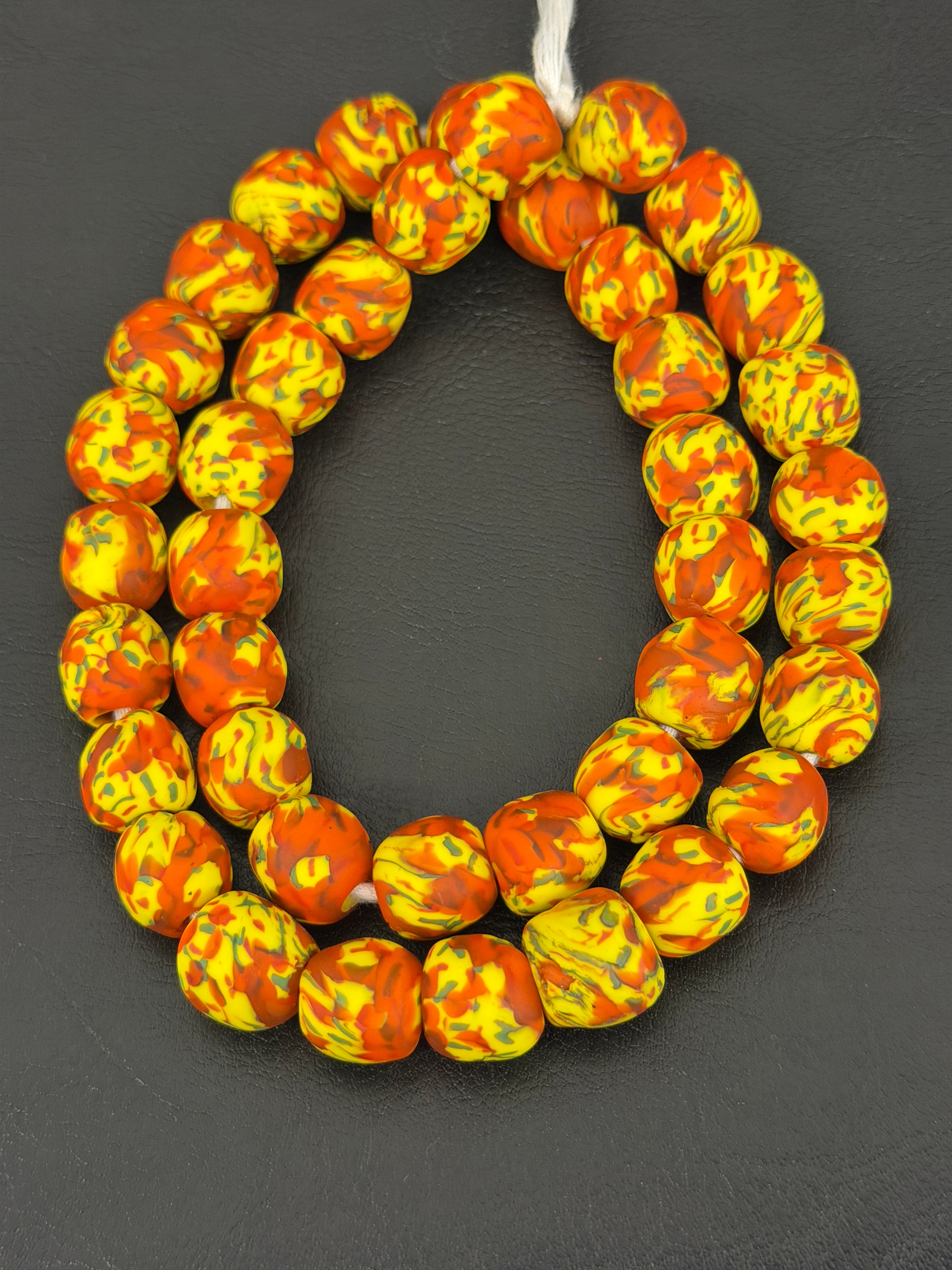 Handcrafted Fused Krobo recycled glass beads from Ghana featuring vibrant yellow and orange marbled patterns on approximately 44 artisan-made beads