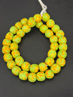 Authentic Fused Krobo recycled glass beads handcrafted in Ghana featuring lime green, golden yellow, and orange fused patterns on approximately 44 artisan-made beads strung on a strand.