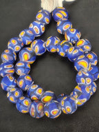 Strand of cobalt blue African trade beads sourced in Ghana featuring layered yellow, white, and red eye motifs, approximately 15–16mm with large 7–8mm holes for jewelry making, collecting, and decorative arts.