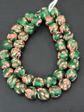 Authentic Fused Krobo recycled glass beads handcrafted in Ghana featuring emerald green, ivory white, and coral artisan patterns on approximately 44 handmade beads strung on a strand.