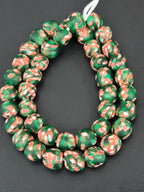 Authentic Fused Krobo recycled glass beads handcrafted in Ghana featuring emerald green, ivory white, and coral artisan patterns on approximately 44 handmade beads strung on a strand.