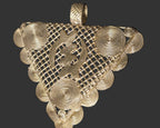 Oversized Ghanaian brass Gye Nyame pendant shown with a scale reference to demonstrate its substantial statement size.