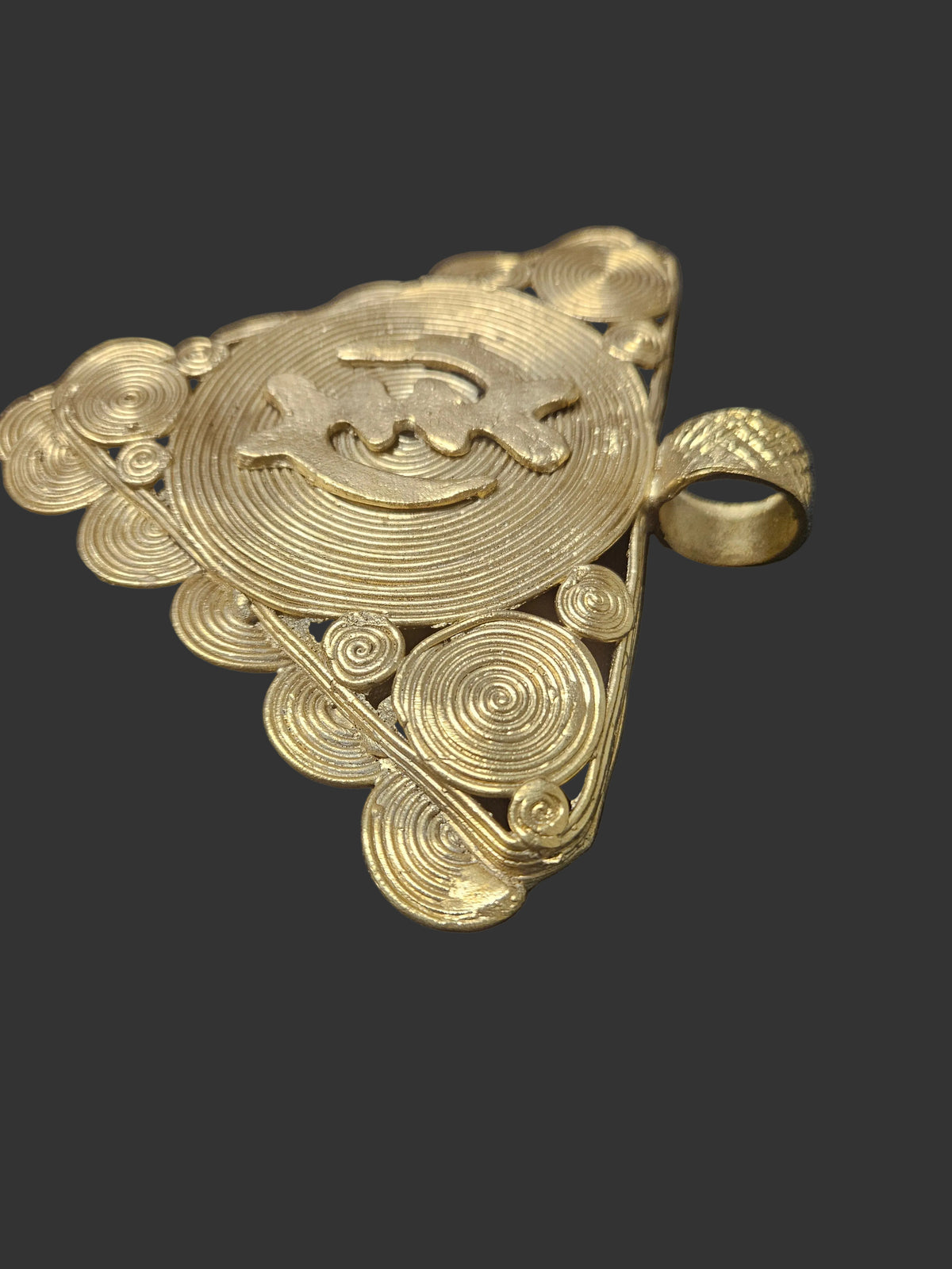 Close-up of the wide textured bail on a handcrafted Gye Nyame brass pendant from Ghana.