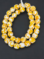 Authentic Fused Krobo recycled glass beads handcrafted in Ghana featuring ivory, golden yellow, and tangerine fused patterns on approximately 44 artisan-made beads strung on a strand.
