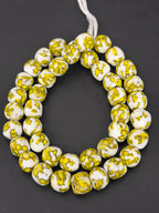 Authentic Fused Krobo recycled glass beads handcrafted in Ghana featuring ivory white and golden yellow artisan patterns on approximately 44 handmade beads strung on a strand.