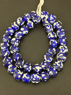 Authentic Fused Krobo recycled glass beads handcrafted in Ghana featuring cobalt blue, ivory white, and black fused patterns on approximately 44 artisan-made beads strung on a strand.