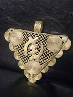 Side view of oversized African brass pendant showing its dimensional handcrafted construction and raised decorative elements.