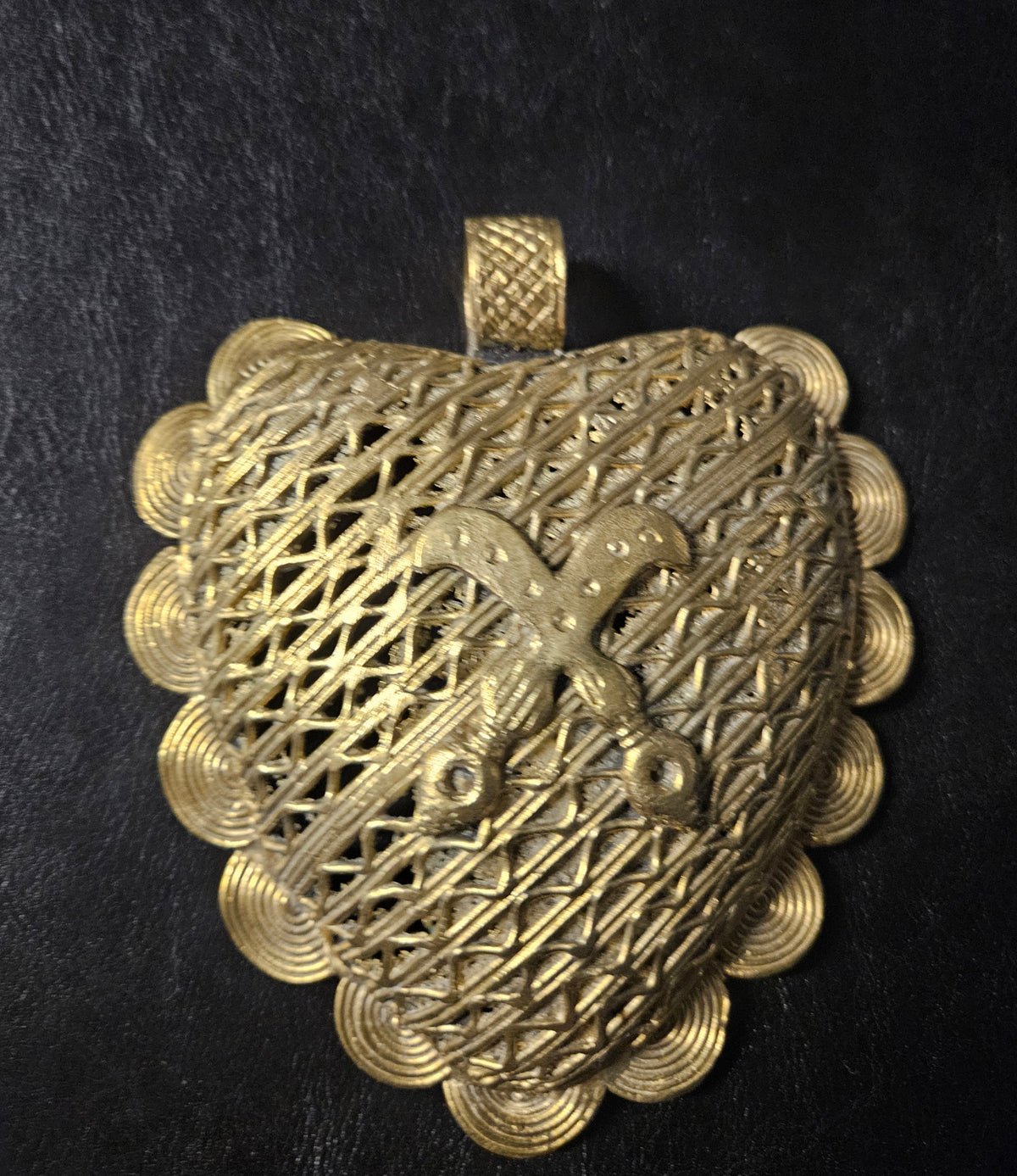 Oversized Akofena Adinkra brass pendant from Ghana with raised crossed-sword motif, layered openwork, spiral border, and textured top bail.