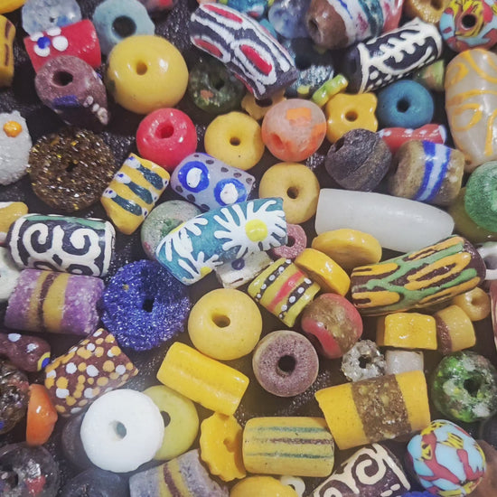 Video close-up highlighting jewel-tone Krobo beads shimmering under light.