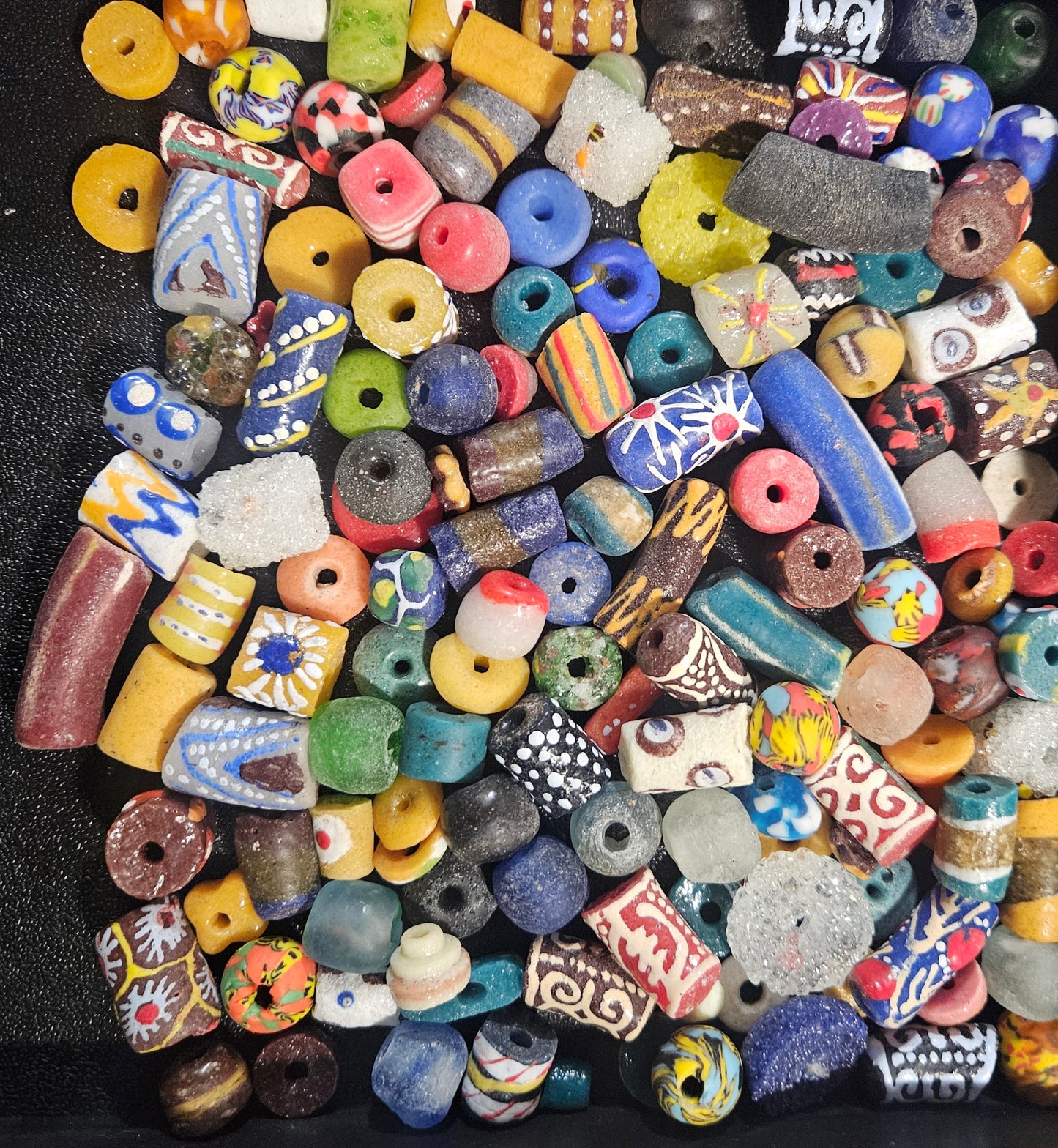 Close-up of layered assorted Krobo artisan beads showing mixed sizes and colors.