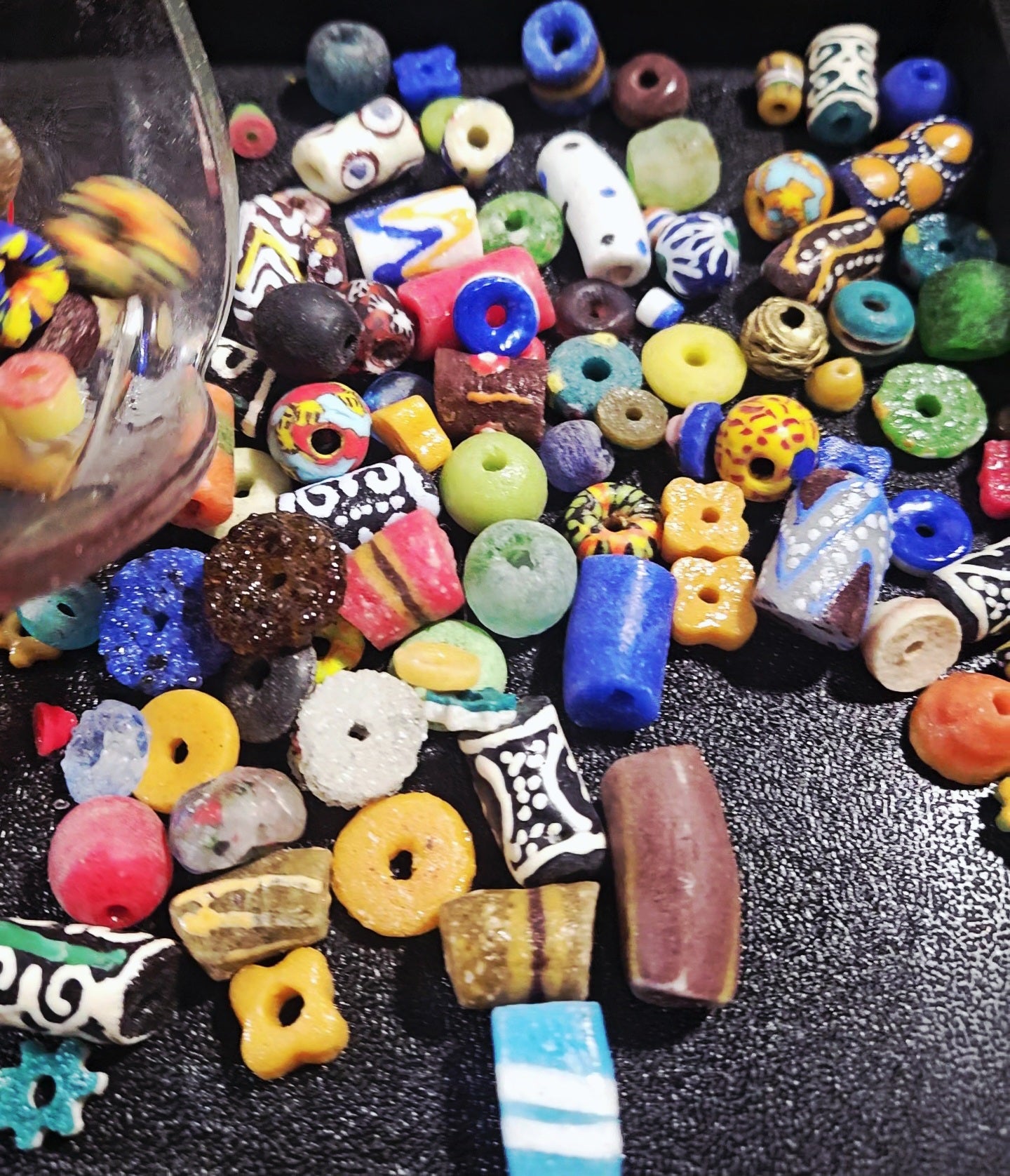 Speckled Krobo beads poured out to show dotted surfaces.