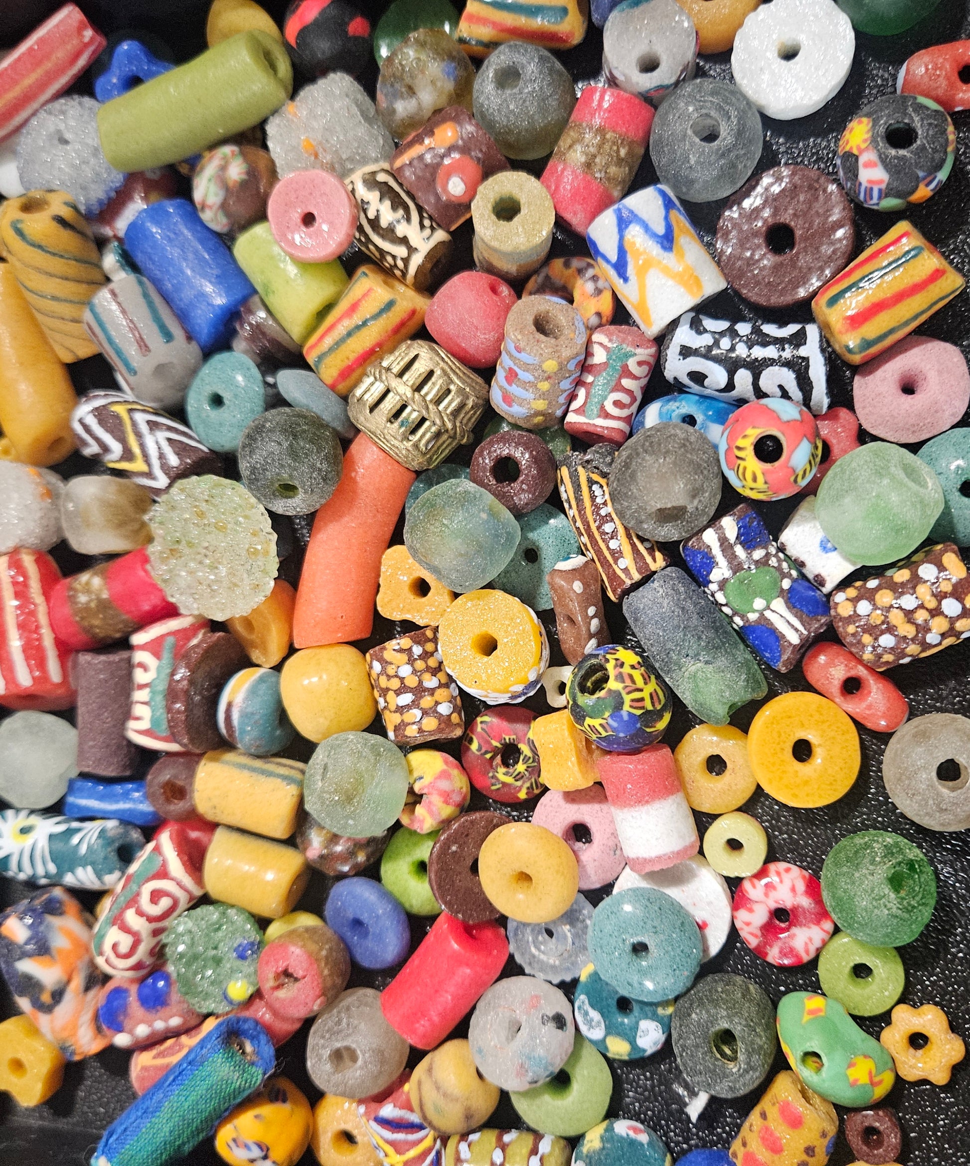 Flat lay of bright festival Krobo recycled glass beads in red, yellow, and blue.