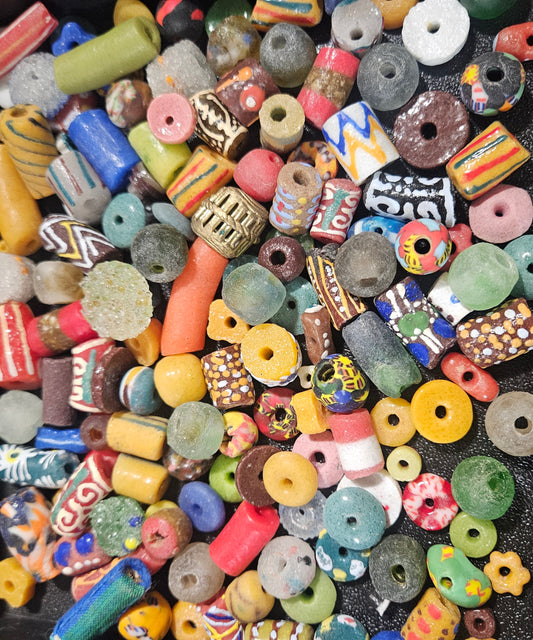 Flat lay of bright festival Krobo recycled glass beads in red, yellow, and blue.