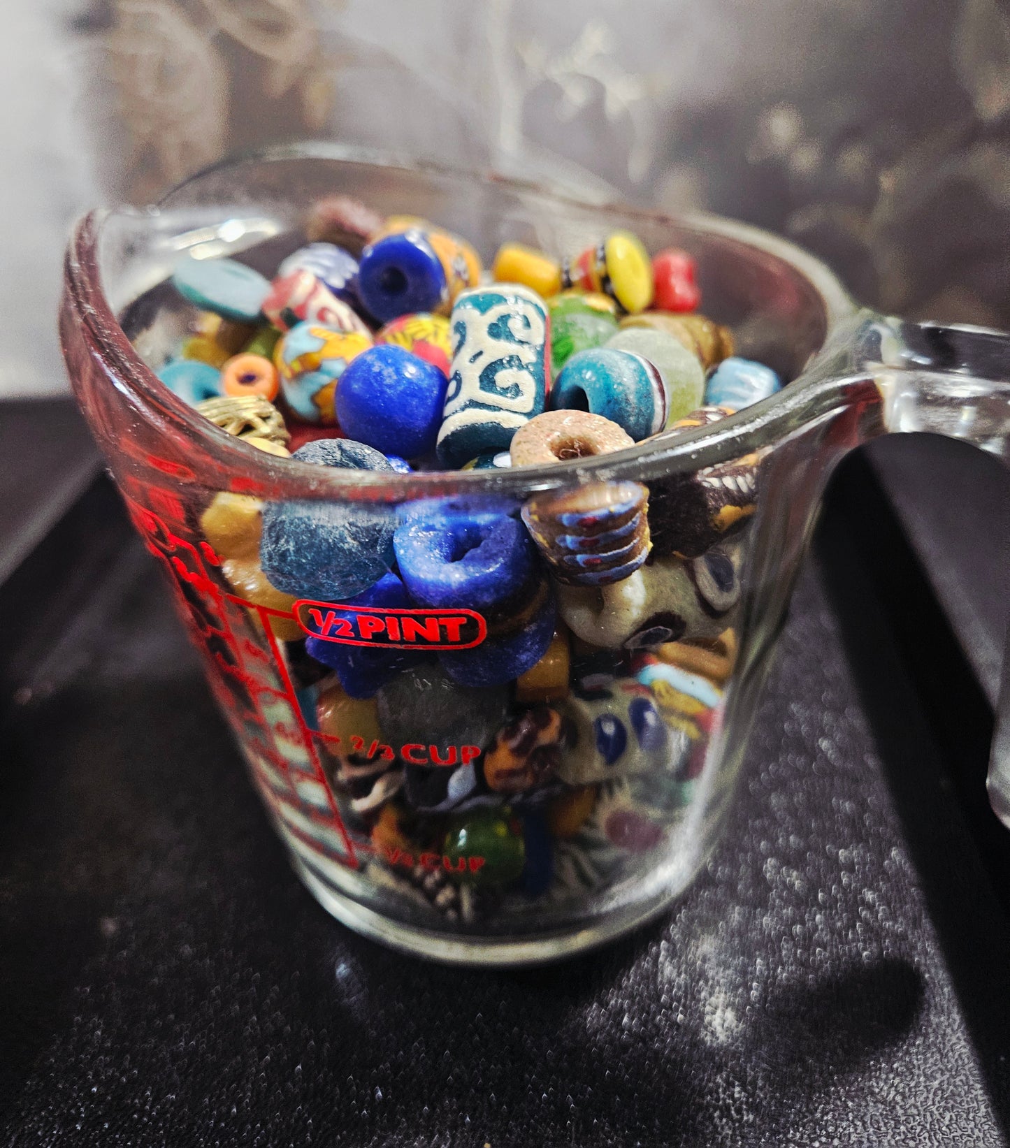 Measuring cup filled with speckled Krobo artisan beads.