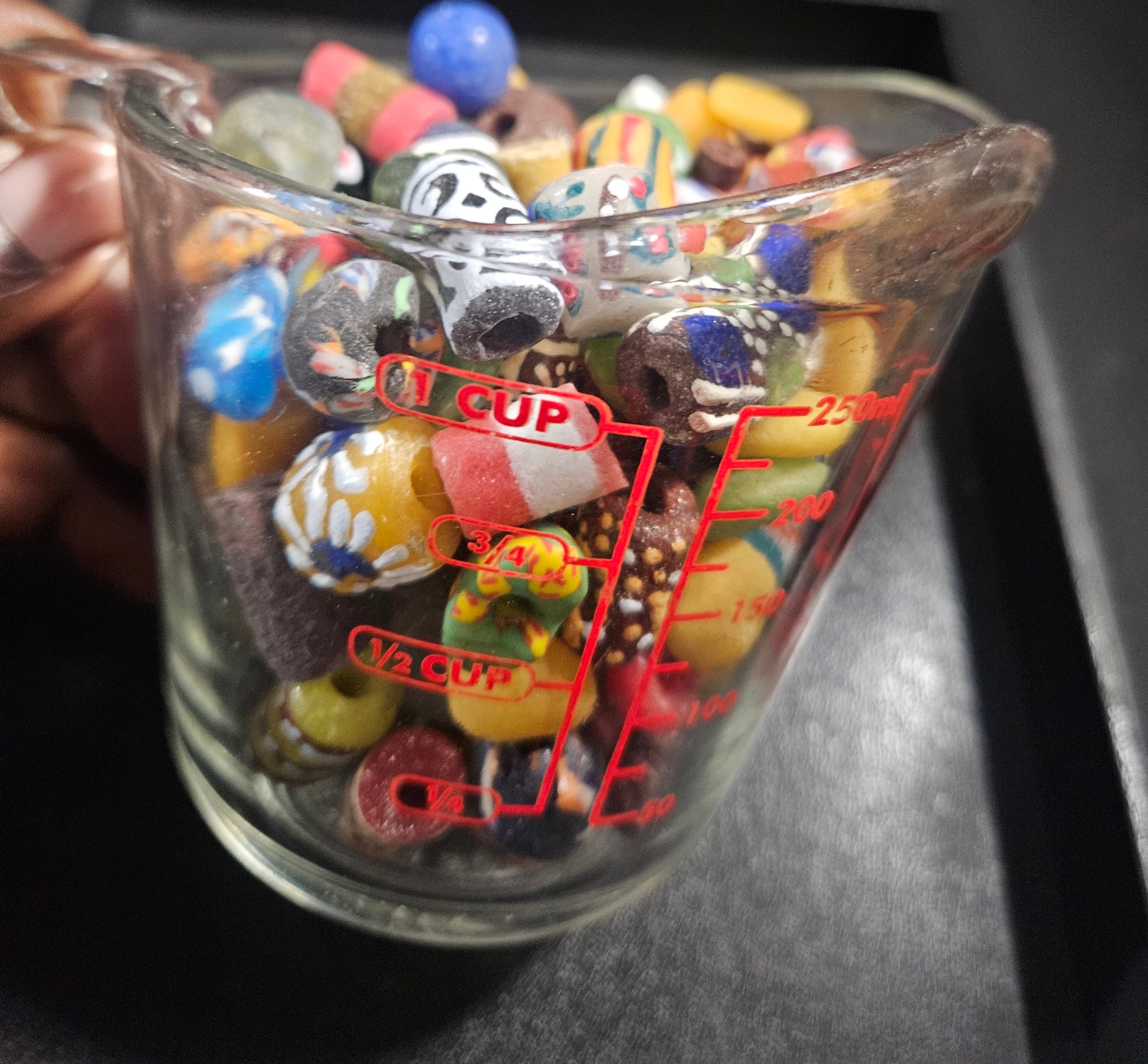 Measuring cup filled with brightly colored Krobo beads.