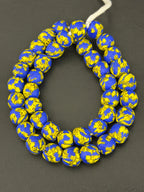 Authentic Fused Krobo recycled glass beads handcrafted in Ghana featuring royal blue and golden yellow fused patterns on approximately 44 artisan-made beads strung on a strand