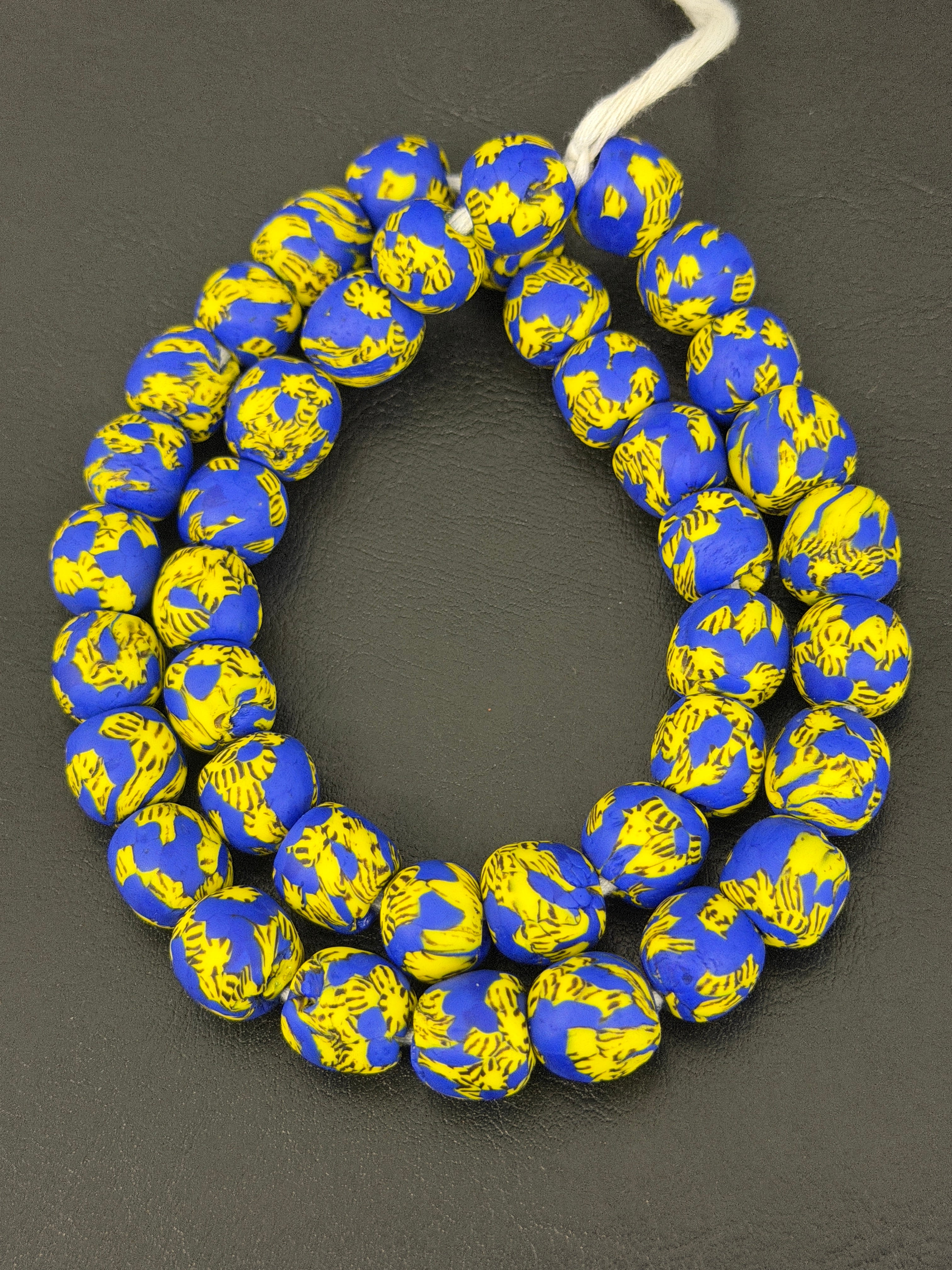 Authentic Fused Krobo recycled glass beads handcrafted in Ghana featuring royal blue and golden yellow fused patterns on approximately 44 artisan-made beads strung on a strand