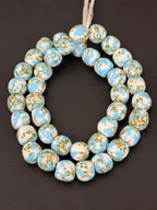 Authentic Fused Krobo recycled glass beads handcrafted in Ghana featuring sky blue, ivory white, and green artisan patterns on approximately 44 handmade beads strung on a strand.