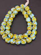 Authentic Fused Krobo recycled glass beads handcrafted in Ghana featuring sky blue and golden yellow fused patterns on approximately 44 artisan-made beads strung on a strand.