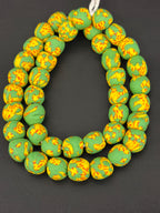 Authentic Fused Krobo recycled glass beads handcrafted in Ghana featuring verdant green and golden yellow fused patterns on approximately 44 artisan-made beads strung on a strand.