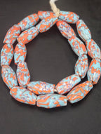 Handcrafted XL orange fused Krobo recycled glass beads from Ghana featuring artisan ivory and charcoal patterns, approximately 12–14mm x 30–34mm.