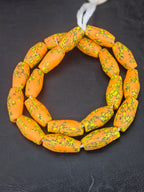 Handcrafted XL orange fused Krobo recycled glass beads from Ghana featuring golden-yellow and charcoal patterns, approximately 12–14mm x 30–34mm.