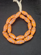 Handcrafted XL orange fused Krobo recycled glass beads from Ghana featuring artisan ivory and charcoal patterns, approximately 12–14mm x 30–34mm.