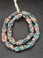 Handcrafted XL teal and coral fused Krobo recycled glass beads from Ghana featuring artisan patterning and elongated barrel-shaped forms.